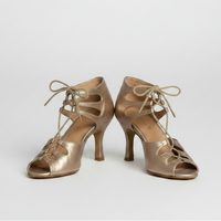 Pair of gold high-heeled shoes with lace-up design on a light background
