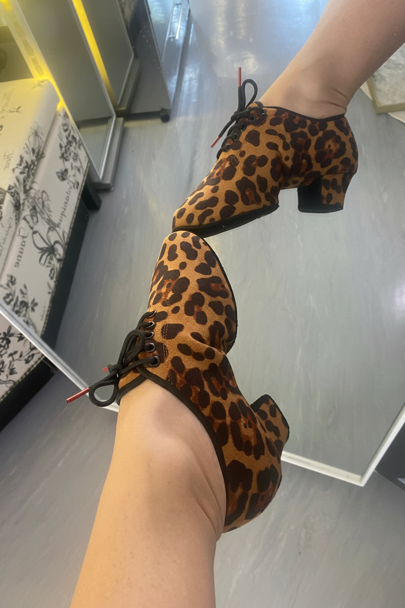 Person pointing foot wearing leopard print practice shoes.