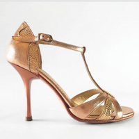 A metallic rose gold high-heeled sandal with a T-strap, ankle buckle, and textured woven panels, shown from a side profile on a white background.
